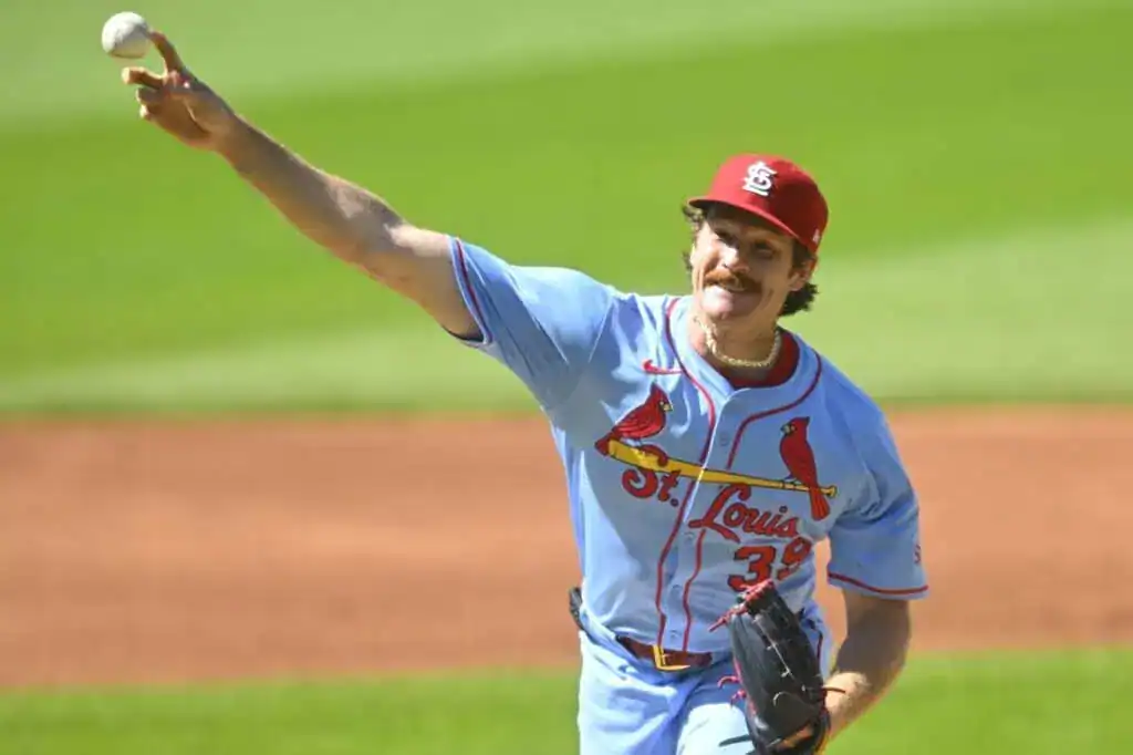 A baseball pitcher in a light blue St. Louis Cardinals jersey prepares to throw a ball on a sunny day at the baseball field.