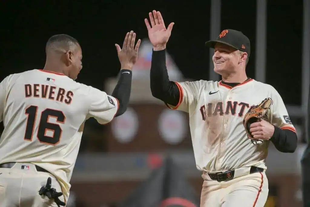 two baseball players, identified as Devers and Cianta, celebrating with a high five. They are likely in a baseball park or field