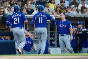 Two baseball players in blue jerseys celebrate on the field, with fans cheering in the background.