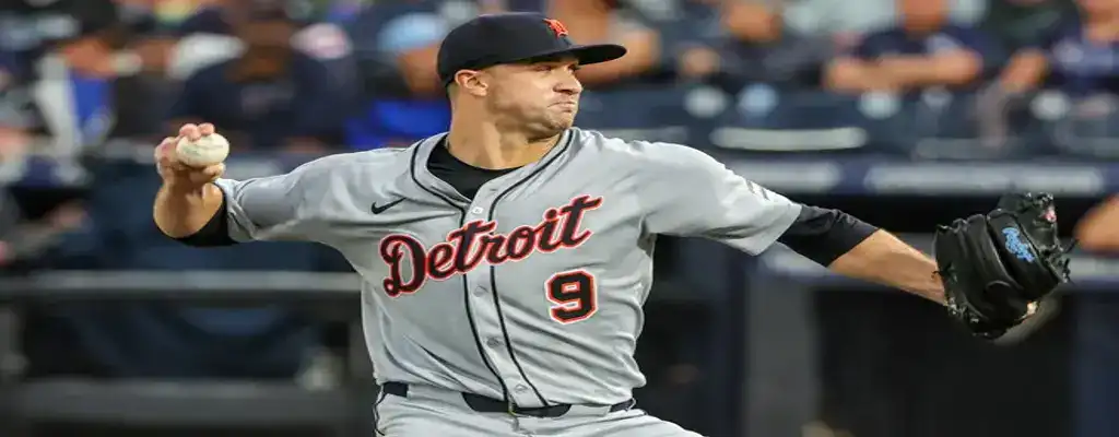 Detroit Tigers pitcher in full motion winding up to throw during a night game