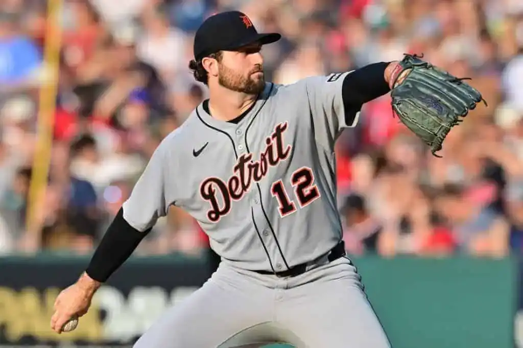 A baseball player is captured throwing a baseball in an outdoor setting, likely on a baseball field or park.