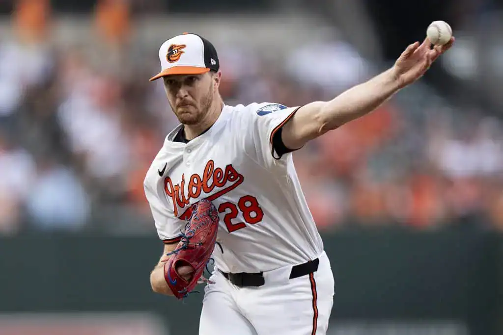 Baltimore Orioles vs Miami Marlins Picks and Predictions July 12th 2025 2 A pitcher in a white Orioles jersey, number 28, throws a baseball on the field during a game, with fans blurred in the background.