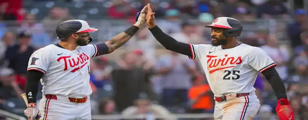 Two Minnesota Twins players celebrating with a high five during a baseball game