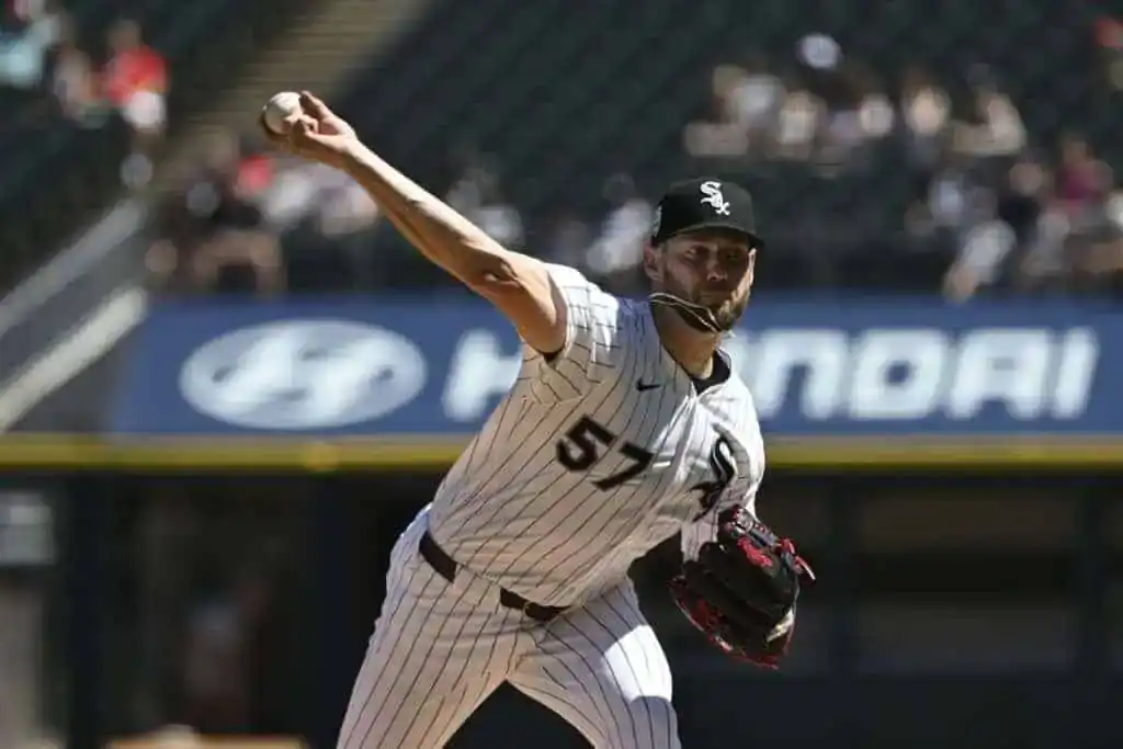 6 A baseball pitcher in a white and black striped uniform throws a ball from the mound, with an empty stadium backdrop.