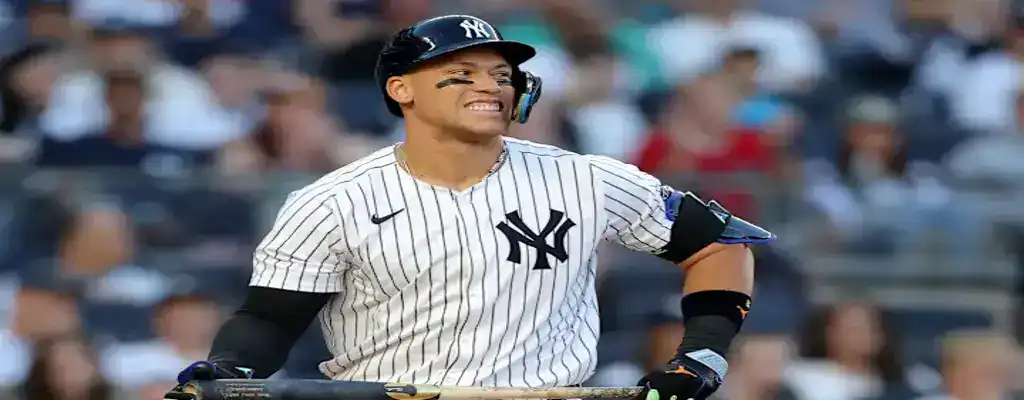 New York Yankees slugger stands at home plate with a grin, bat resting in front of him