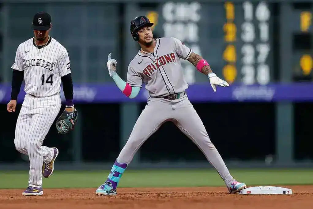 An Arizona Diamondbacks player gestures toward the dugout while standing on second base, with a Colorado Rockies player nearby.