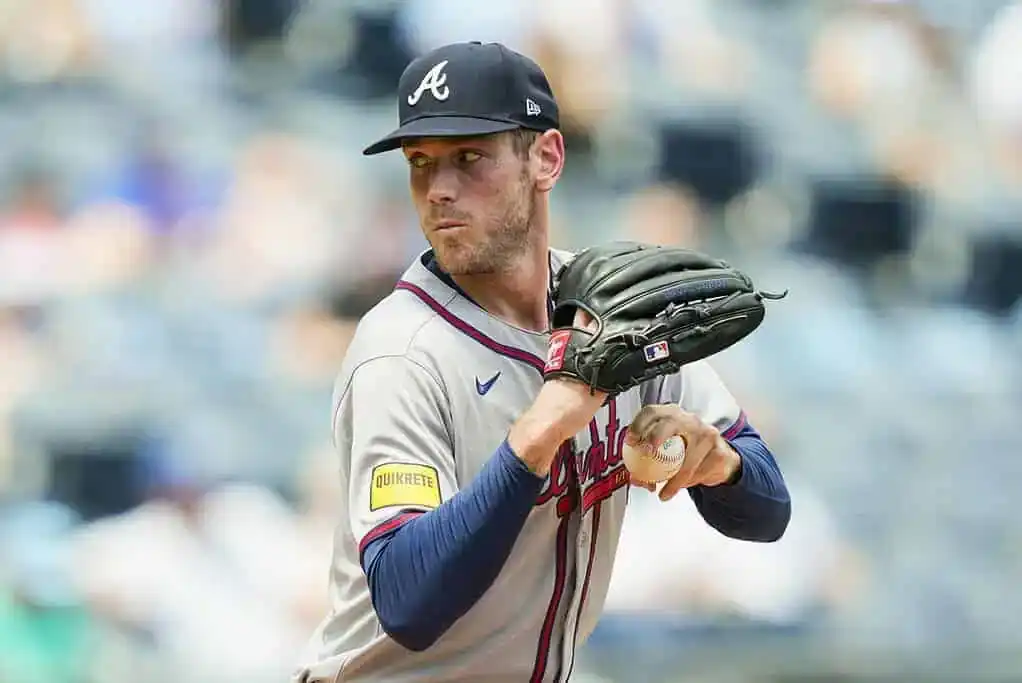 A pitcher in a gray Atlanta Braves jersey prepares to throw a baseball during a game in a crowded stadium.