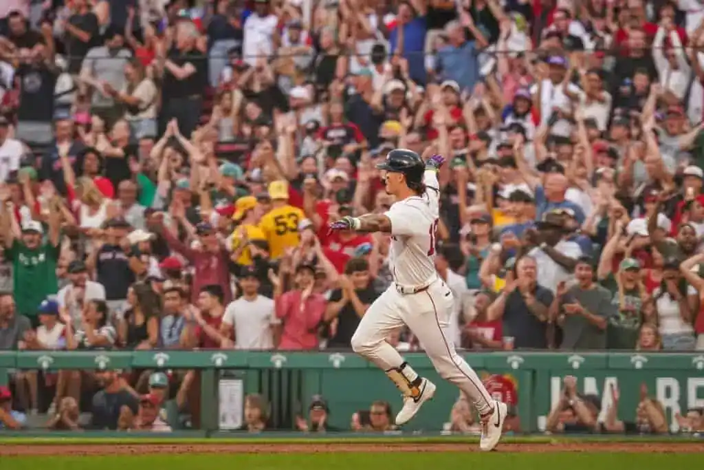 A baseball player celebrates as a jubilant crowd of fans cheers, with hands raised and excitement evident throughout the stadium.