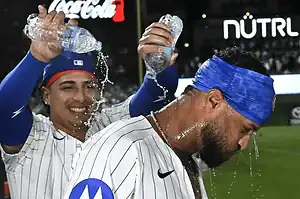 Cubs players pour water on teammate after game.