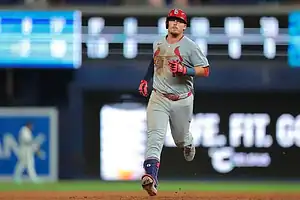 St. Louis Cardinals player runs the bases in a gray road uniform.