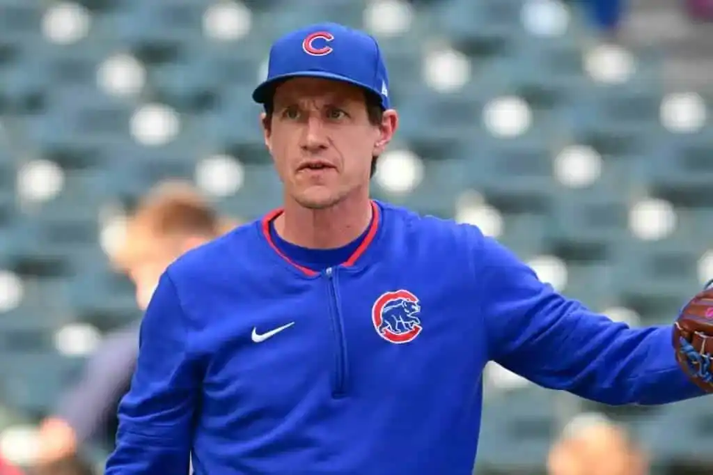 A person wearing a blue Chicago Cubs jacket and cap stands on a baseball field, ready to throw a baseball.