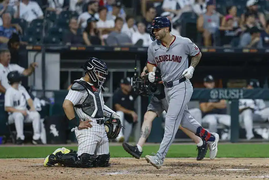 Cleveland Indians player runs past White Sox catcher at home plate.