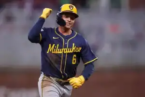 A baseball player in a blue and yellow Milwaukee jersey celebrates a play, with a fist pump and a look of determination.