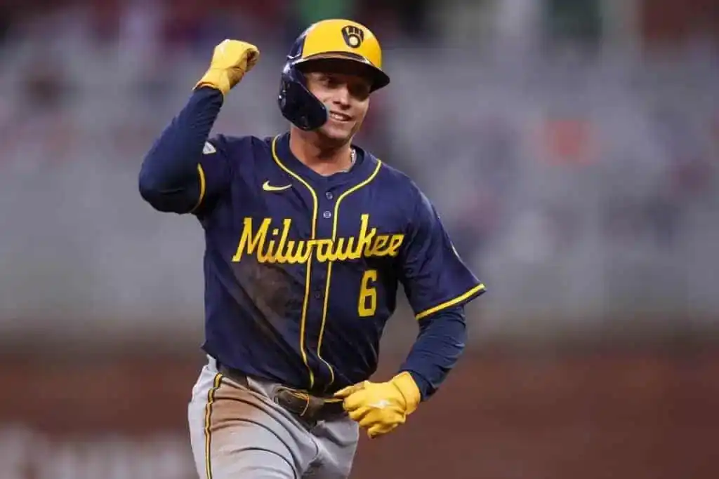 A baseball player in a blue and yellow Milwaukee jersey celebrates a play, with a fist pump and a look of determination.