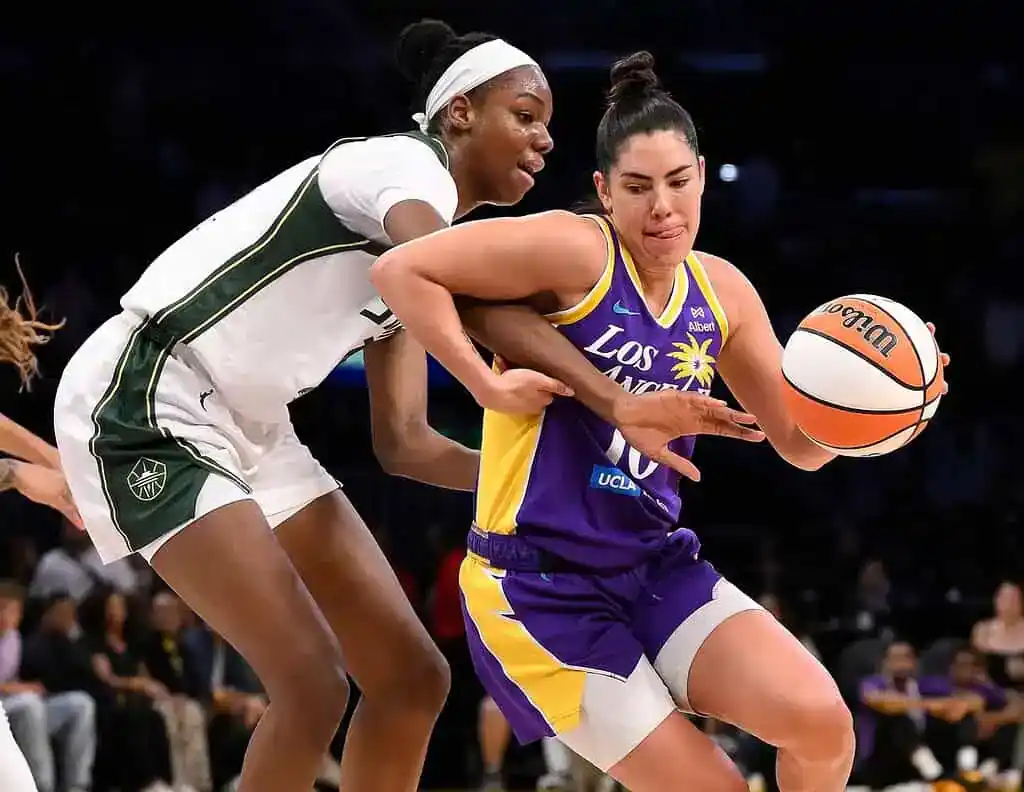 Two female basketball players compete for the ball on the court, showcasing athleticism and teamwork during a game.