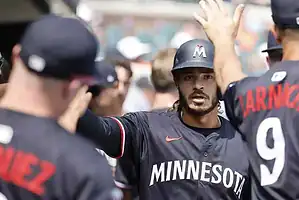 A group of baseball players in black jerseys celebrate together, showcasing team spirit and excitement during a game.