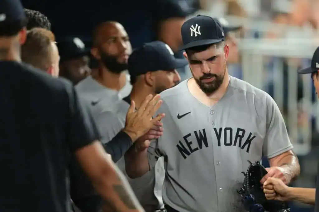 A group of baseball players in gray jerseys with "NEW YORK" on the front, celebrating a teammate in a lively dugout atmosphere.