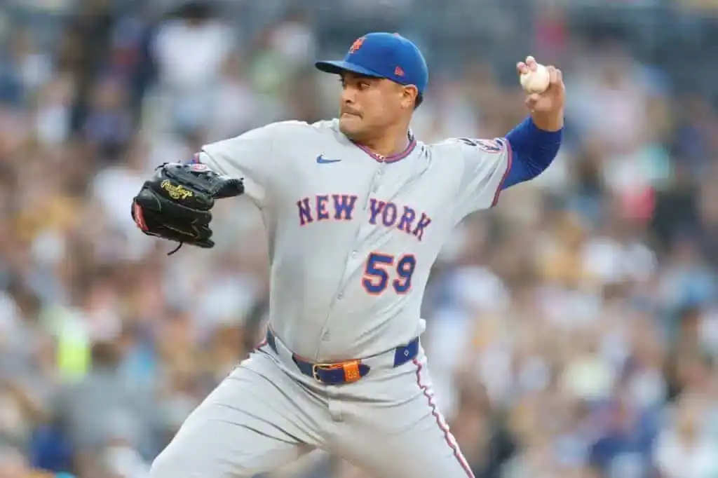 A New York Mets pitcher in a gray jersey and cap prepares to throw a baseball on the field during a game.