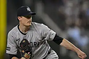 A New York Yankees pitcher prepares to throw, wearing a gray jersey and holding a black glove on the mound during a game.