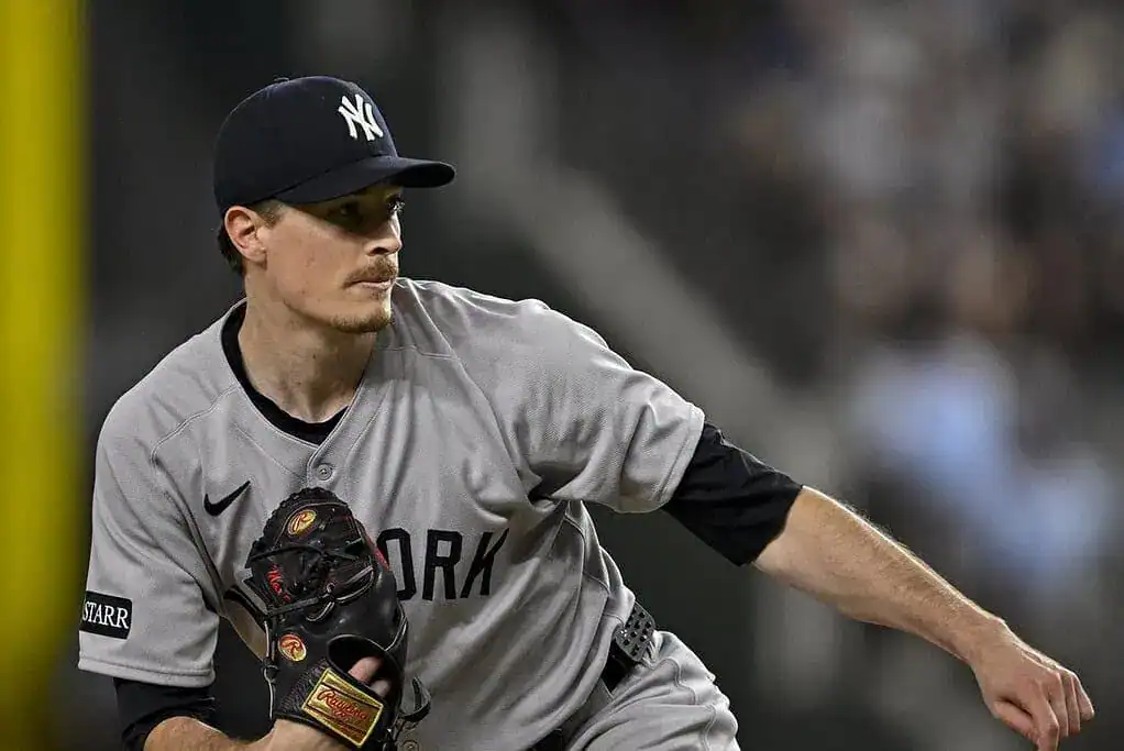 A New York Yankees pitcher prepares to throw, wearing a gray jersey and holding a black glove on the mound during a game.