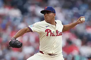 Philadelphia Phillies pitcher delivering a pitch in full motion during a game.