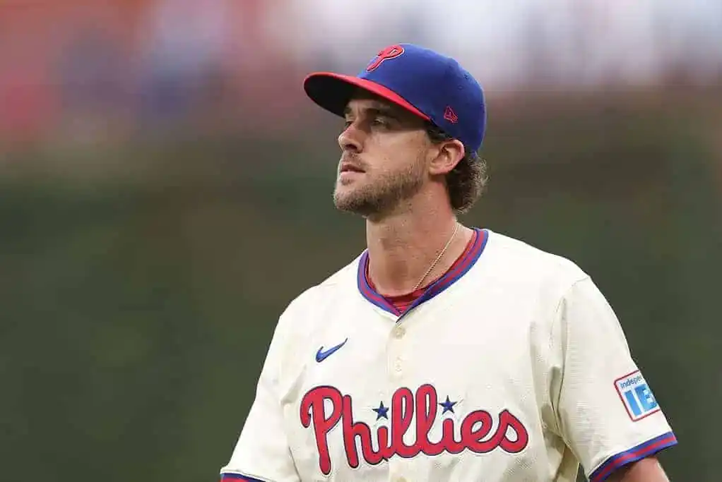 Philadelphia Phillies player looks frustrated on the field during an MLB game, wearing a cream-colored uniform with a red cap.