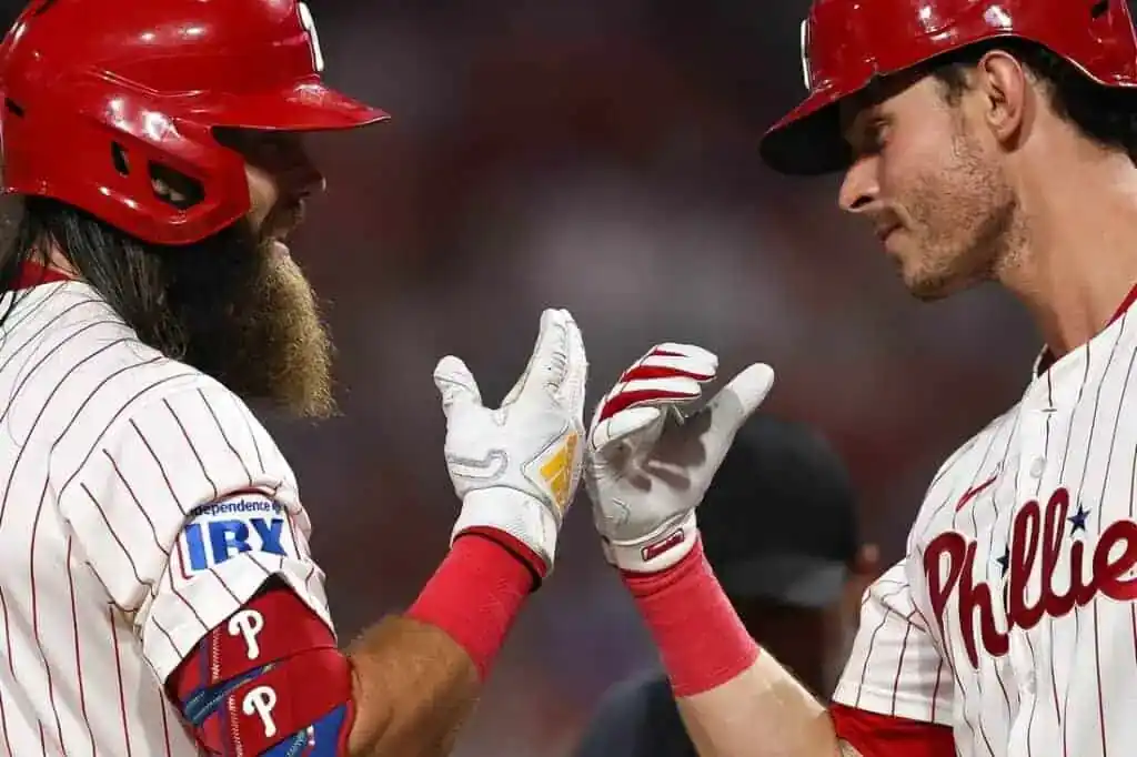 Two baseball players in red and white uniforms are celebrating with a high five, showcasing their excitement in a game setting.