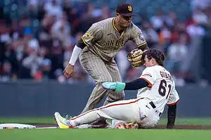 A San Diego Padres player fields the ball, while a San Francisco Giants player slides into base, showcasing intense baseball action.