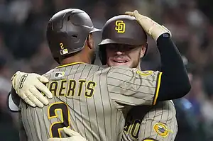 Two baseball players in striped uniforms celebrate a victory with a joyful embrace on the field.