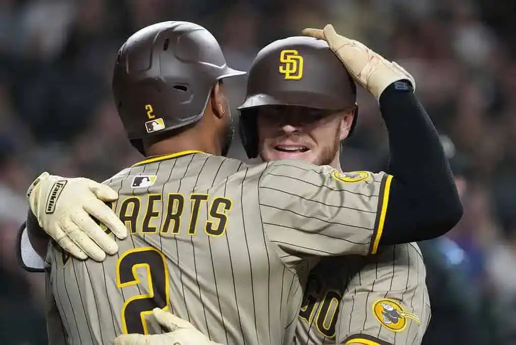 Two baseball players in striped uniforms celebrate a victory with a joyful embrace on the field.