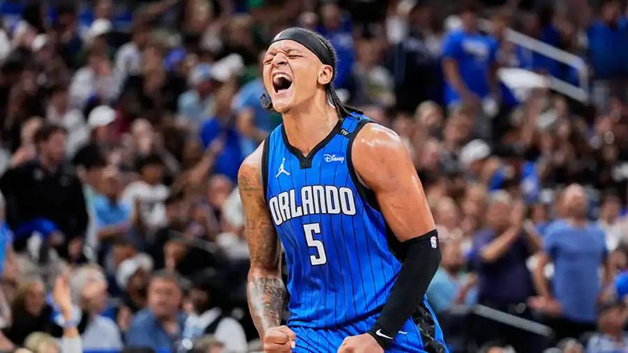 Orlando Magic player number 5 shouts in celebration, fists clenched, with a cheering crowd behind him.
