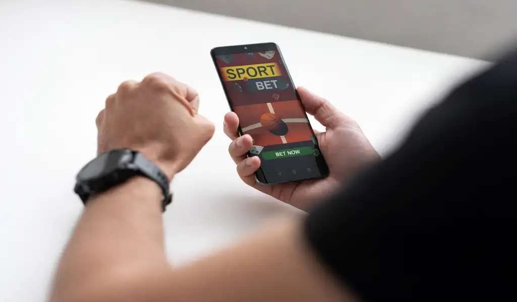 Person using a sports betting app on a smartphone, representing what competition and better betting options mean for bettors.