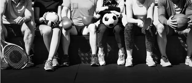 Group of sports fans holding football, soccer ball, basketball, tennis racket, and boxing gloves, illustrating different factors bettors consider when comparing sportsbook value.